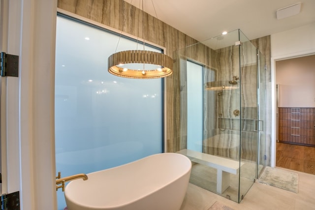 bathroom with shower with separate bathtub, tile patterned floors, and tile walls