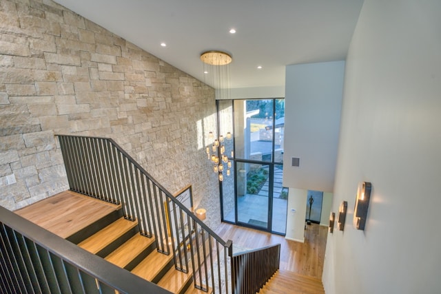 stairs featuring wood-type flooring and high vaulted ceiling