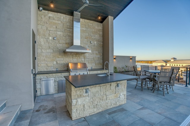 patio terrace at dusk featuring ceiling fan, grilling area, an outdoor kitchen, and sink