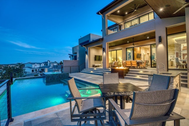 pool at dusk featuring an outdoor hangout area, sink, ceiling fan, and a patio area