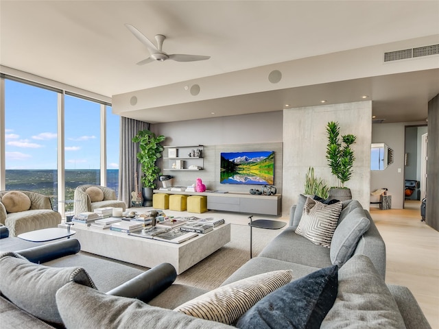 living room with ceiling fan, a wall of windows, and light hardwood / wood-style flooring