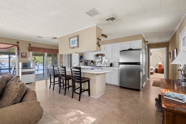 kitchen with a kitchen breakfast bar, white cabinets, appliances with stainless steel finishes, and crown molding