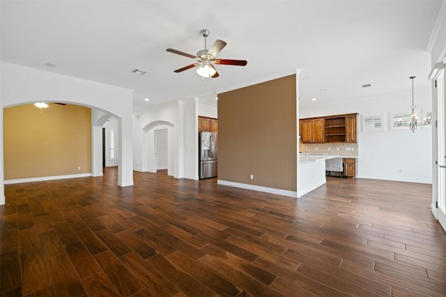 unfurnished living room with sink, dark hardwood / wood-style flooring, ceiling fan with notable chandelier, and crown molding