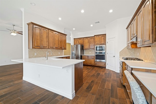 kitchen with appliances with stainless steel finishes, dark hardwood / wood-style floors, ceiling fan, and backsplash