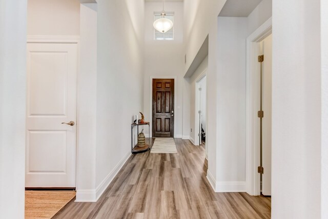 entryway with light wood-type flooring, a high ceiling, and baseboards