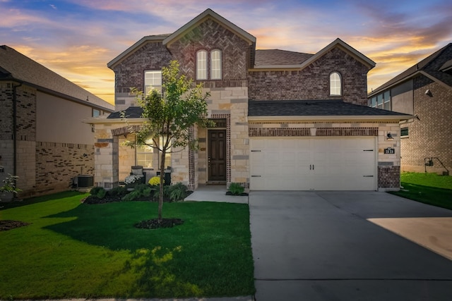 french provincial home with stone siding, concrete driveway, brick siding, and a lawn