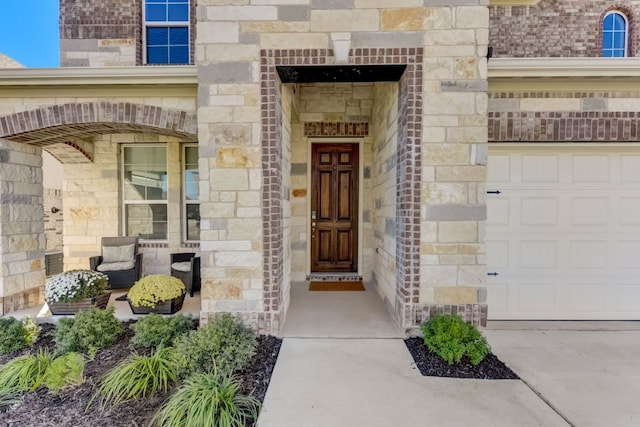 view of exterior entry featuring a garage and stone siding