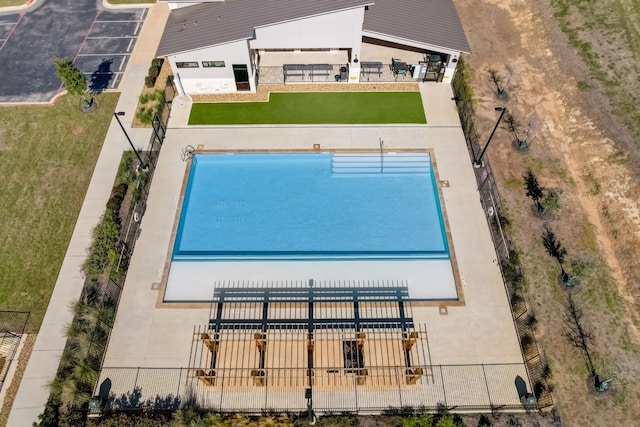 view of swimming pool with fence and a lawn