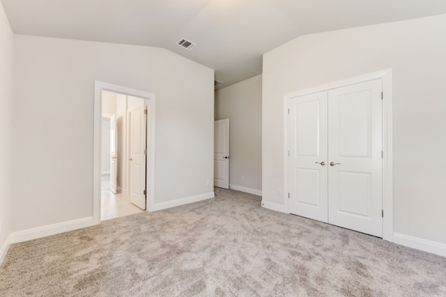 unfurnished bedroom featuring baseboards, visible vents, lofted ceiling, carpet, and a closet