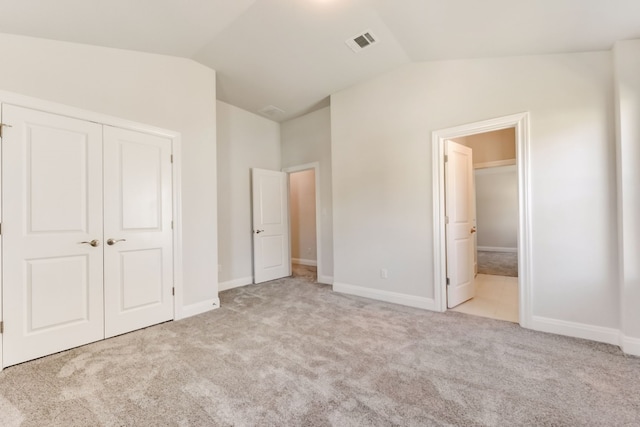 unfurnished bedroom featuring a closet, visible vents, vaulted ceiling, and carpet flooring