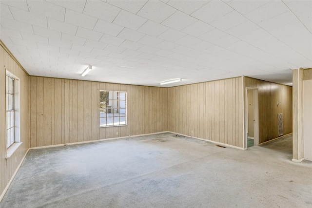 carpeted spare room featuring wooden walls