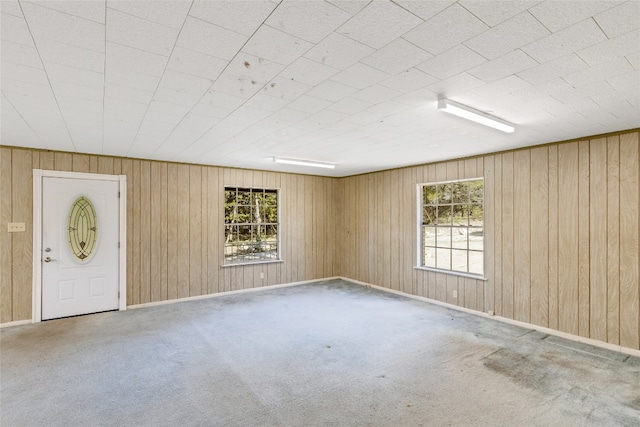 carpeted spare room with wooden walls