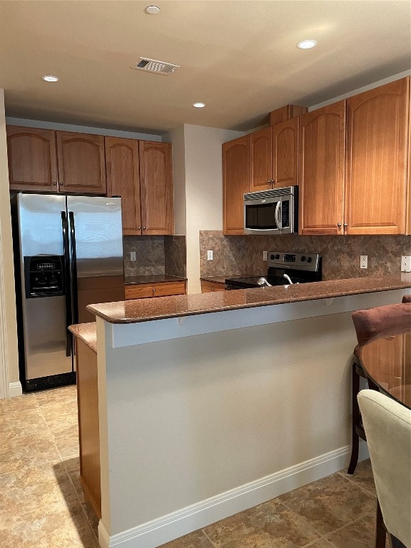 kitchen featuring light tile patterned floors, kitchen peninsula, tasteful backsplash, and stainless steel appliances