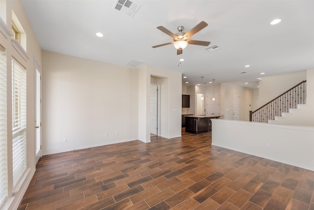 unfurnished living room with ceiling fan and dark wood-type flooring