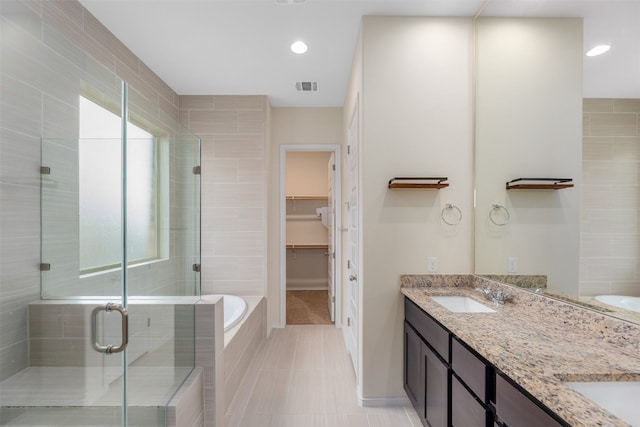 bathroom with plus walk in shower, double sink vanity, tile patterned floors, and tile walls