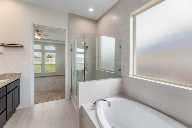 bathroom featuring tile walls, tile patterned flooring, vanity, ceiling fan, and plus walk in shower