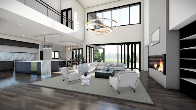 living room with dark wood finished floors, a high ceiling, a glass covered fireplace, and a notable chandelier