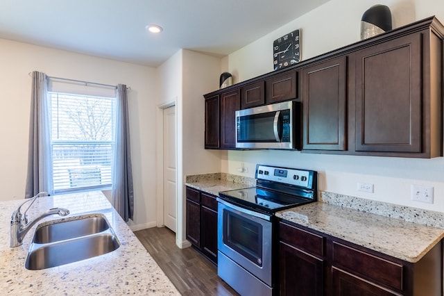 kitchen with light stone counters, dark brown cabinetry, stainless steel appliances, dark wood-type flooring, and sink