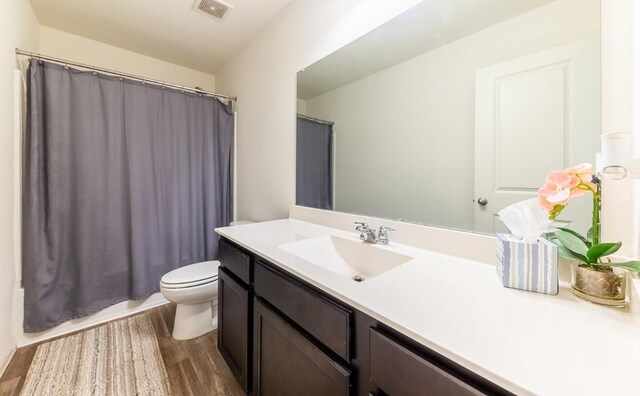 full bathroom featuring vanity, hardwood / wood-style flooring, toilet, and shower / tub combo with curtain