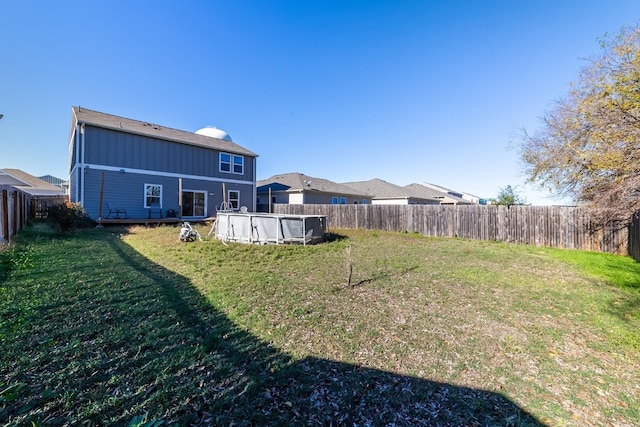 rear view of property with a fenced in pool and a lawn