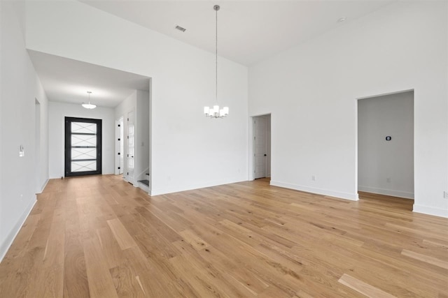 interior space featuring a chandelier, a high ceiling, and light hardwood / wood-style flooring