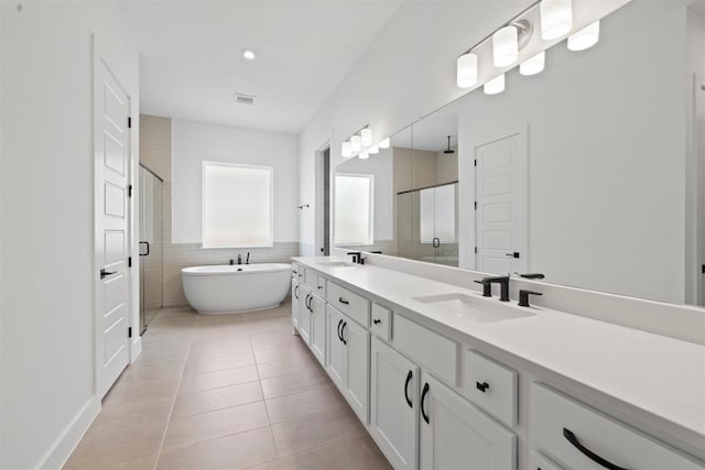 bathroom featuring tile patterned flooring, shower with separate bathtub, vanity, and tile walls