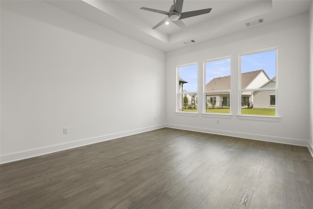 spare room featuring dark wood-type flooring, ceiling fan, and a tray ceiling