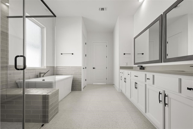 bathroom featuring tile walls, independent shower and bath, and vanity