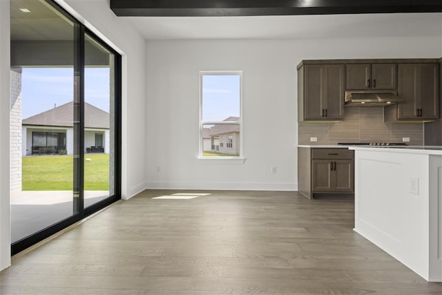 kitchen with dark brown cabinetry, stainless steel gas cooktop, light wood-type flooring, and tasteful backsplash