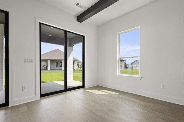 unfurnished room featuring a wealth of natural light, beam ceiling, and light wood-type flooring