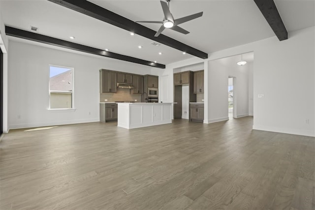 unfurnished living room with ceiling fan, beamed ceiling, sink, and wood-type flooring