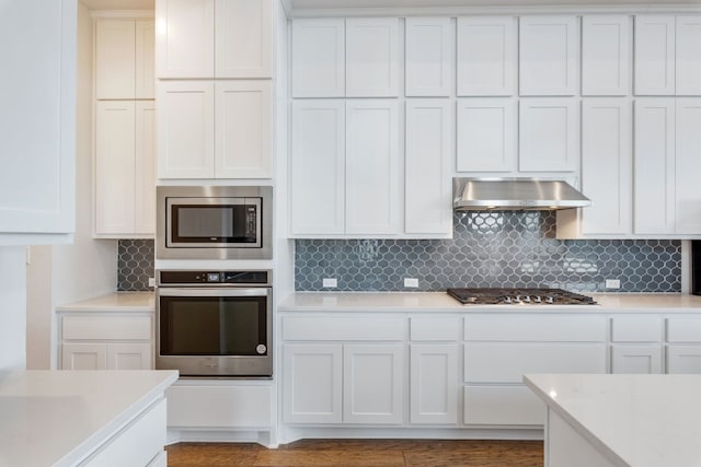 kitchen with wall chimney exhaust hood, white cabinetry, and stainless steel appliances