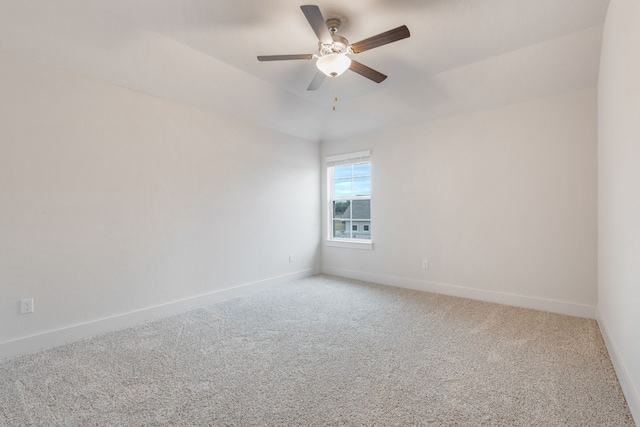 carpeted spare room with a tray ceiling, a ceiling fan, and baseboards