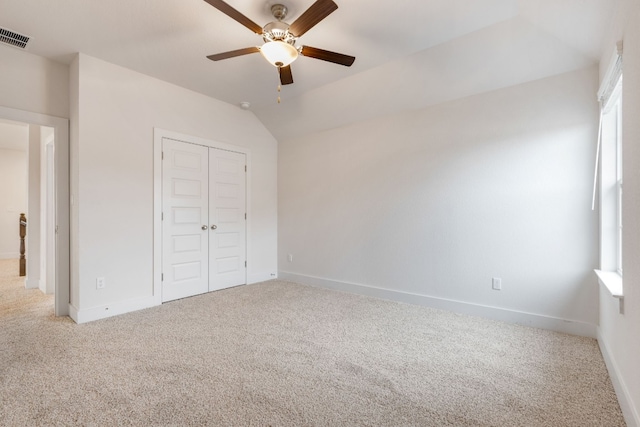 unfurnished bedroom featuring a closet, visible vents, light carpet, vaulted ceiling, and baseboards