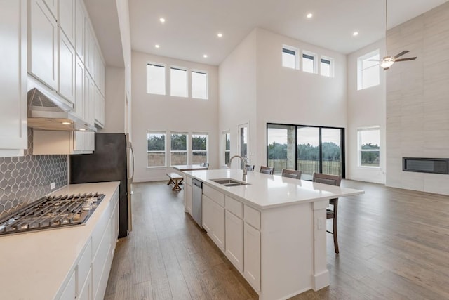 kitchen featuring a center island with sink, stainless steel appliances, light countertops, white cabinetry, and a sink