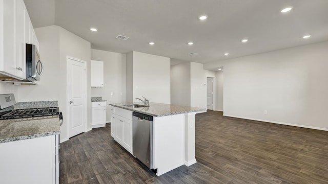 kitchen with a center island with sink, light stone counters, appliances with stainless steel finishes, white cabinets, and dark hardwood / wood-style floors