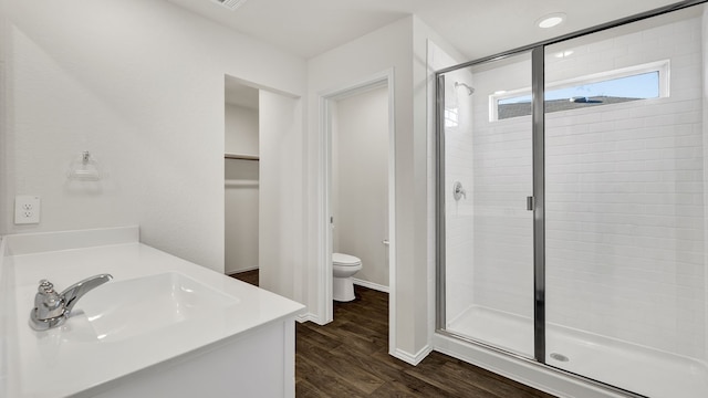 bathroom featuring toilet, hardwood / wood-style flooring, walk in shower, and vanity