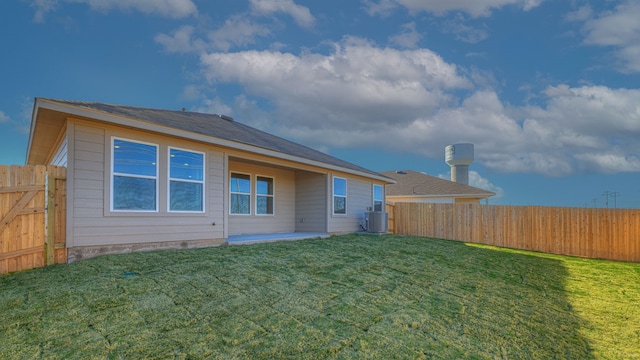 rear view of house with central air condition unit and a yard