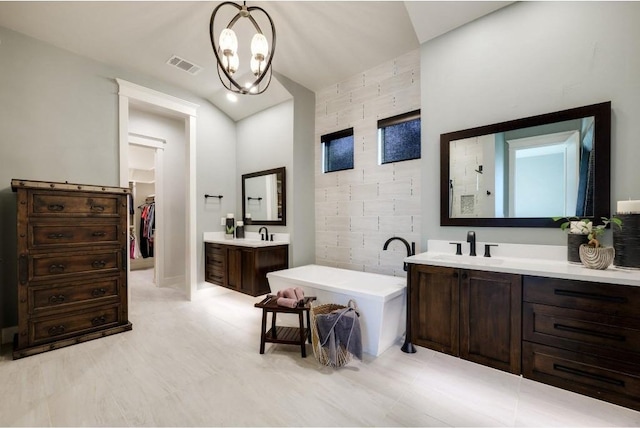 bathroom featuring a washtub, vanity, vaulted ceiling, and a notable chandelier