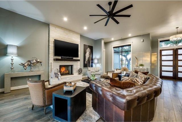 living room featuring wood-type flooring, a stone fireplace, french doors, and ceiling fan