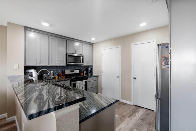 kitchen featuring tasteful backsplash, kitchen peninsula, appliances with stainless steel finishes, and gray cabinetry