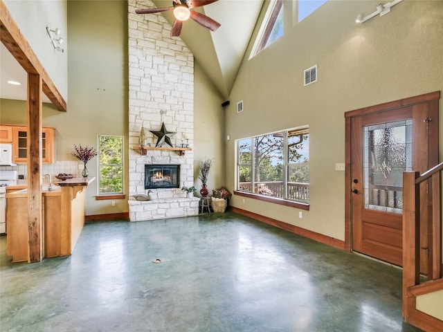 living room with a stone fireplace, high vaulted ceiling, ceiling fan, and sink