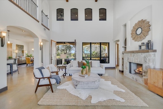 living room with a stone fireplace and a towering ceiling