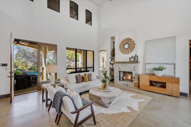 living room with a stone fireplace and a high ceiling