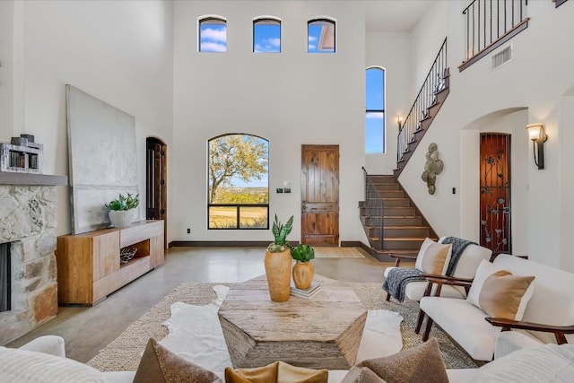 living room with a stone fireplace and a towering ceiling