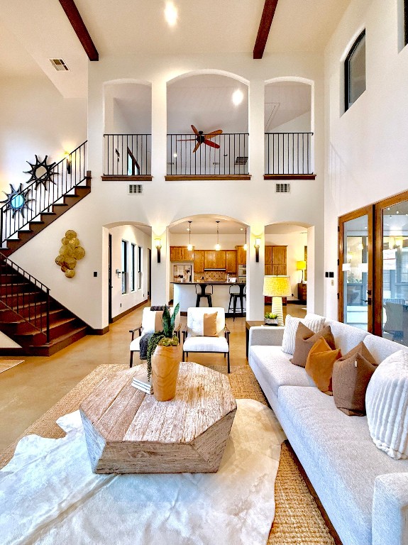 living room featuring beam ceiling and a high ceiling