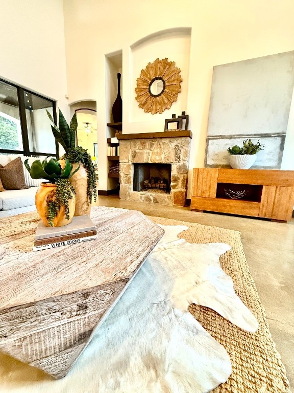 living room with a stone fireplace and a towering ceiling