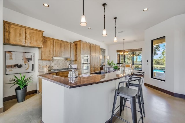 kitchen with sink, a chandelier, hanging light fixtures, appliances with stainless steel finishes, and decorative backsplash