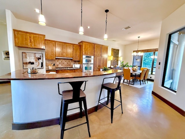 kitchen with a breakfast bar, tasteful backsplash, pendant lighting, stainless steel appliances, and a large island