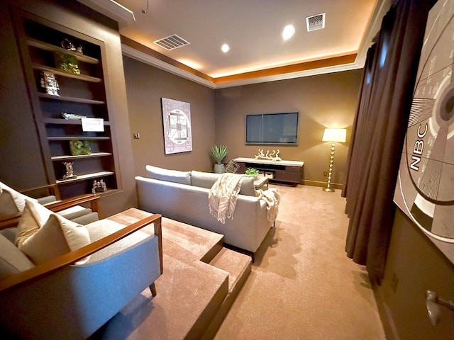 home theater room with crown molding, light colored carpet, and built in shelves